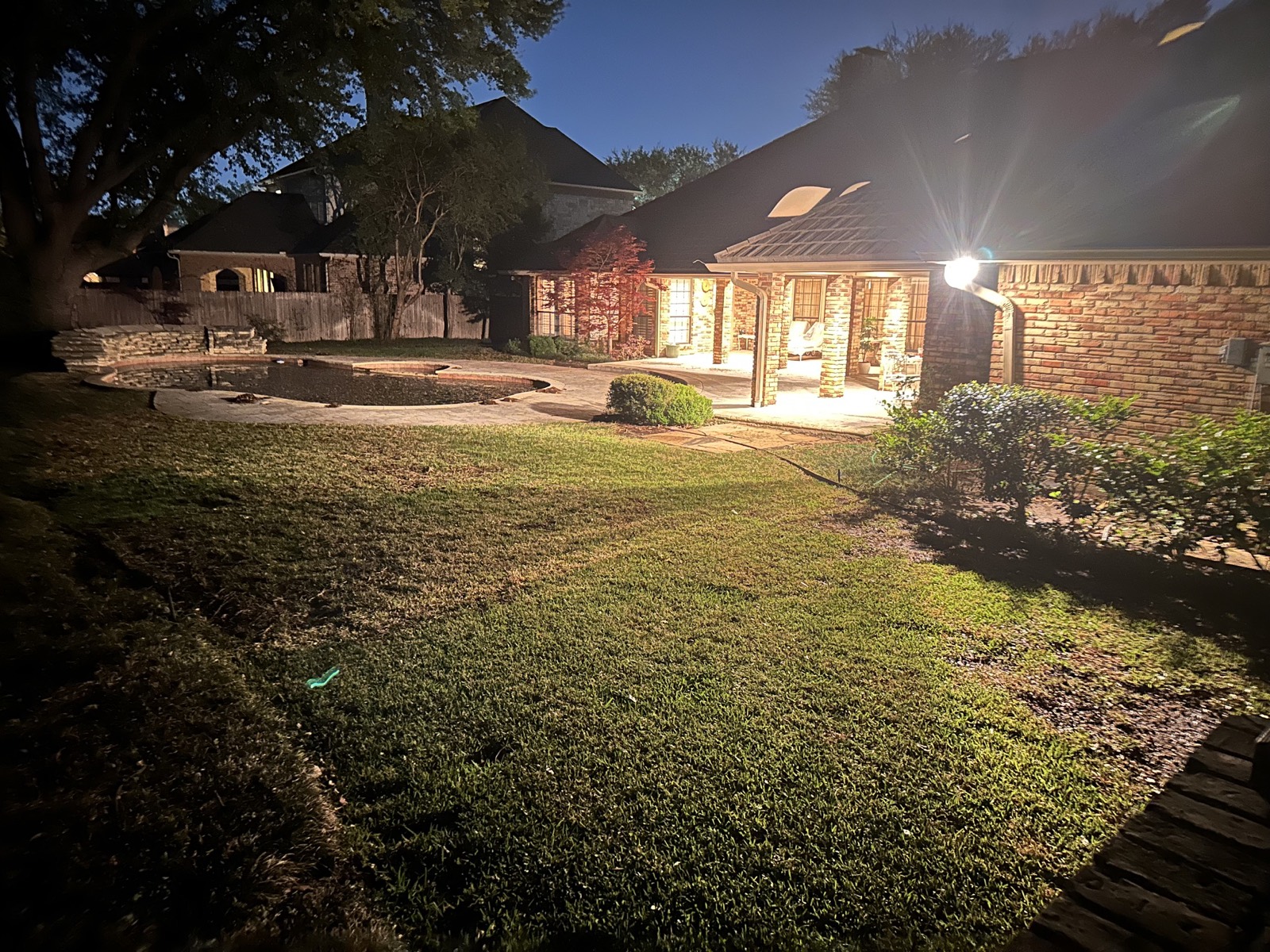 Backyard patio and pool lit at dusk