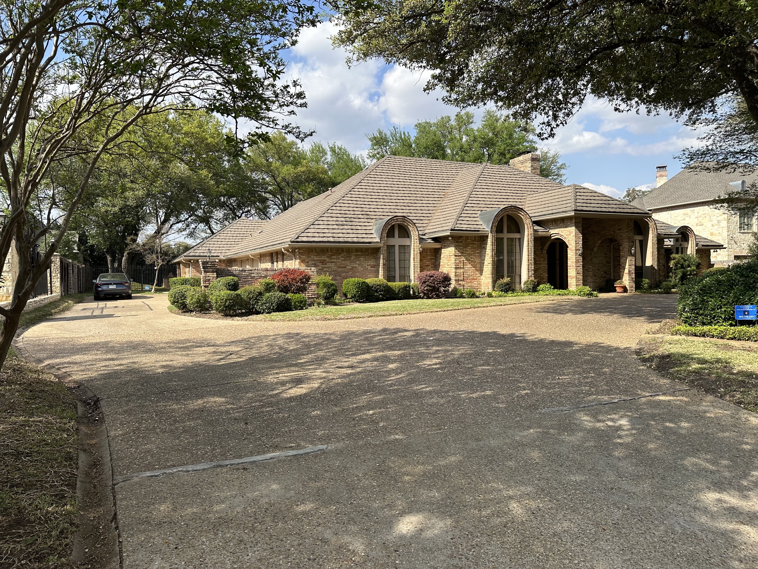 Front exterior of 5321 Bent Tree Drive, a one-story brick estate shaded by mature oaks